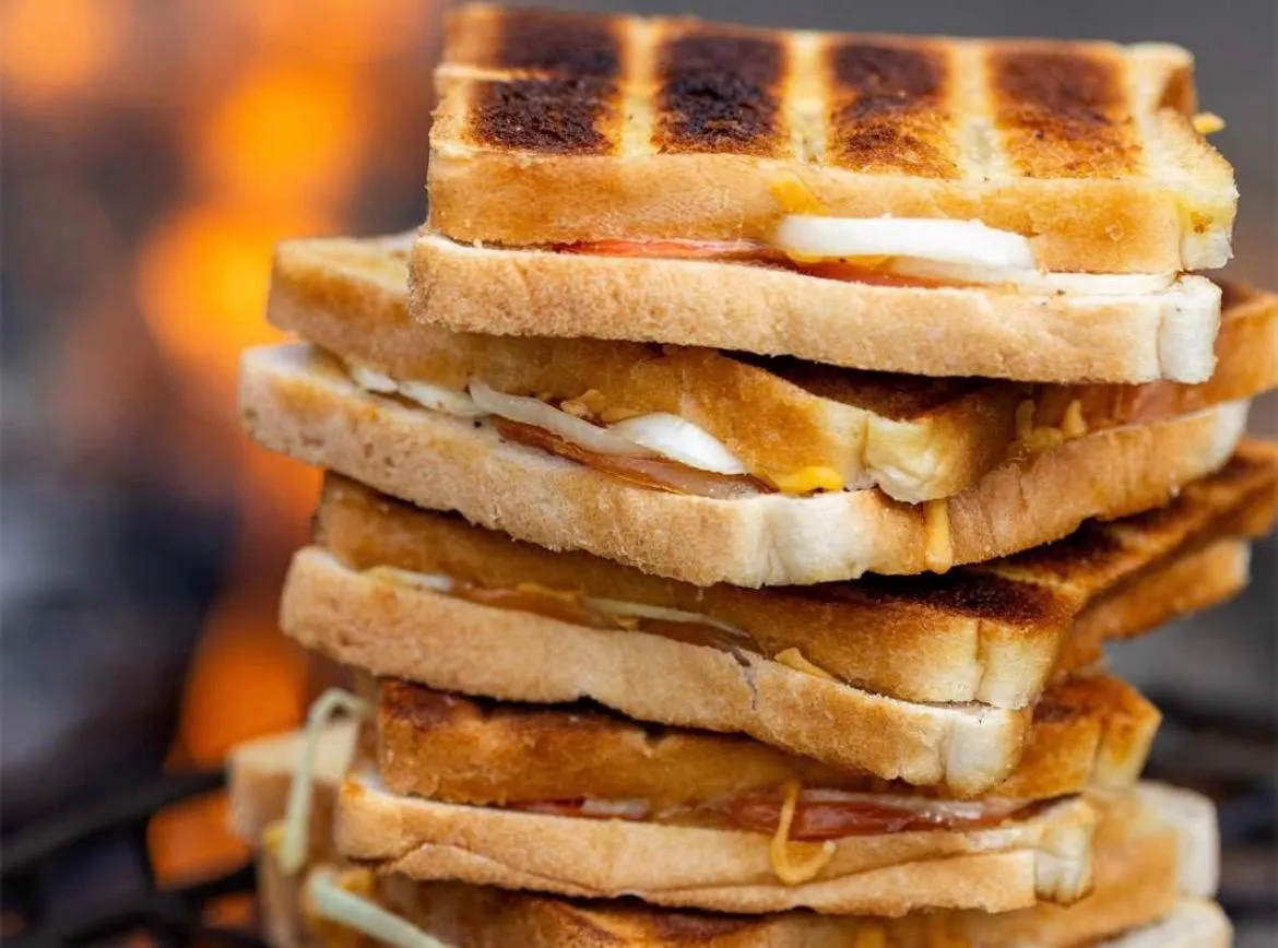 Stack of golden braaibroodjies (grilled sandwiches) with cheese and tomato